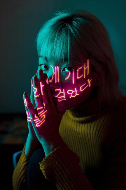 Asian women with chinese letter led lights over her face showing a praying pose with her hands